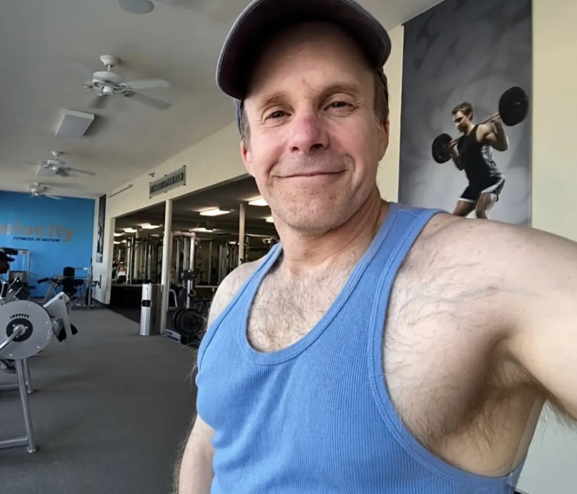 A man in blue shirt and hat standing next to a skateboard.